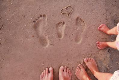 Empreintes dans le sable avec un cœur dessiné.