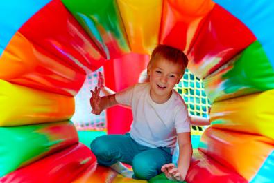 Enfant jouant dans un tunnel gonflable coloré.