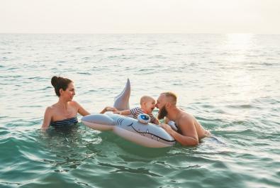 Famille heureuse joue dans la mer avec une bouée en forme de requin.